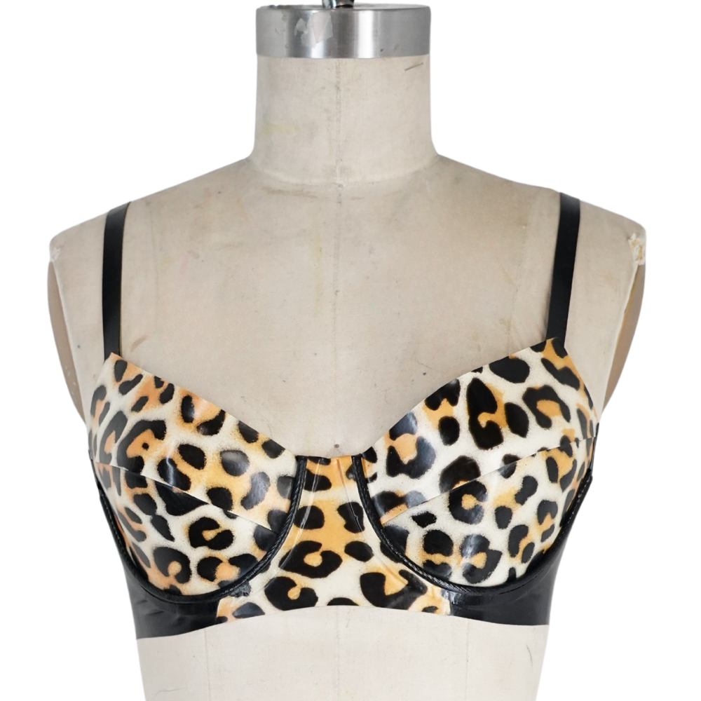 A mannequin torso showcases a Vex Inc. | Latex Clothing leopard print bra with black straps, side panels, underwire, and structured cups—a bold latex lingerie piece ready to ship for those craving a fierce look.