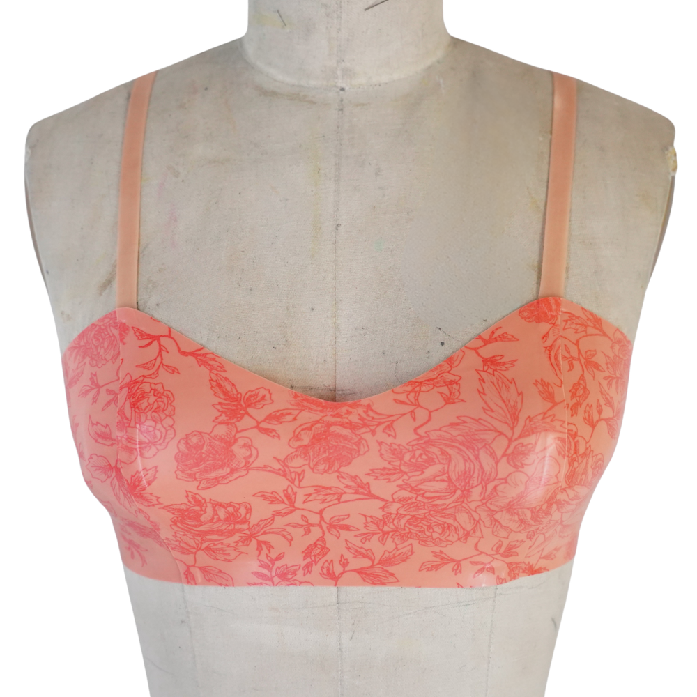 A mannequin showcases a Vex Clothing, INC peach bralette with thin straps and a delicate red floral pattern on the front, ready to ship for your lingerie collection.