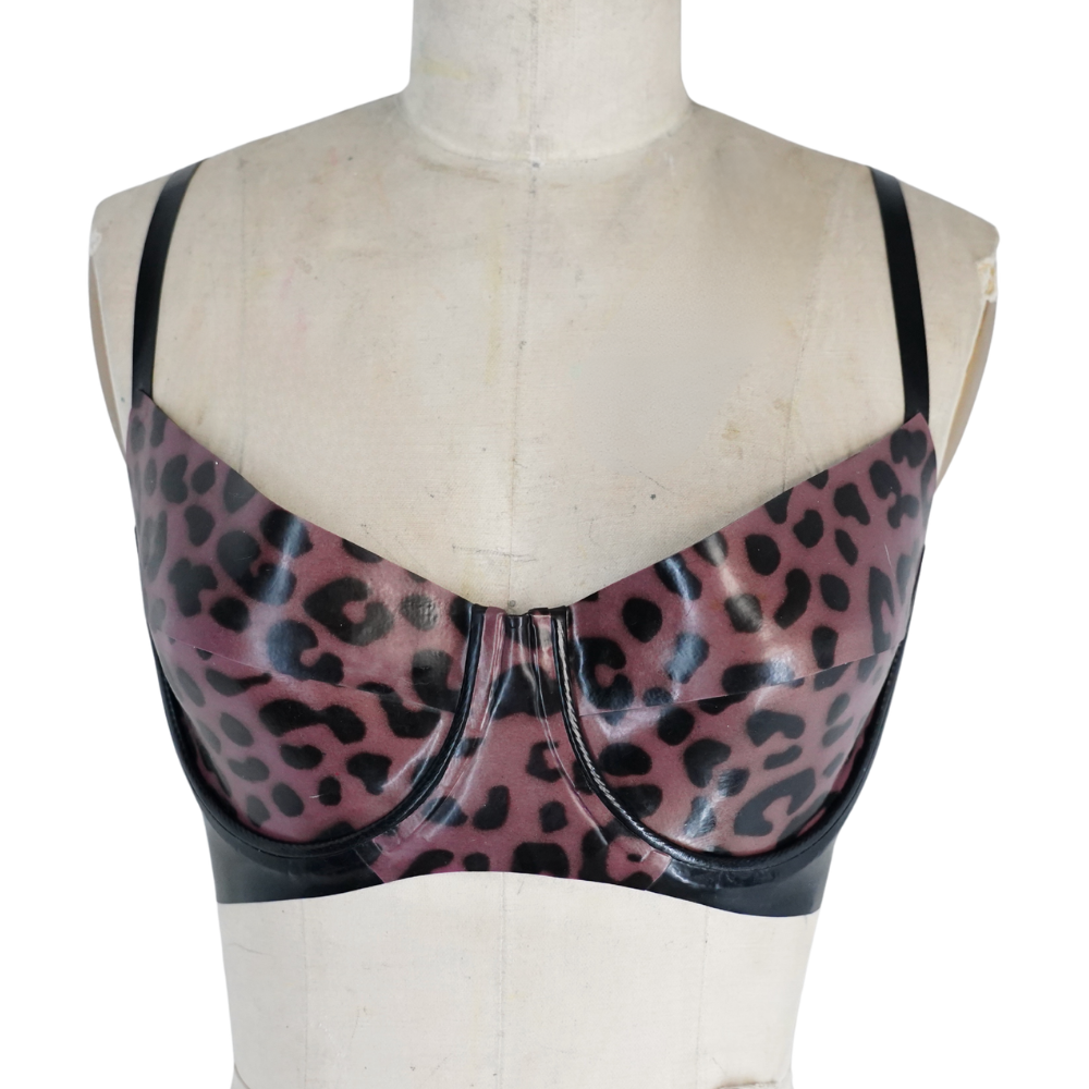 A mannequin torso features a shiny pink and black leopard print bralette with black straps and trim by Vex Inc. | Latex Clothing—perfect to accent your collection, and ready to ship for fast delivery.