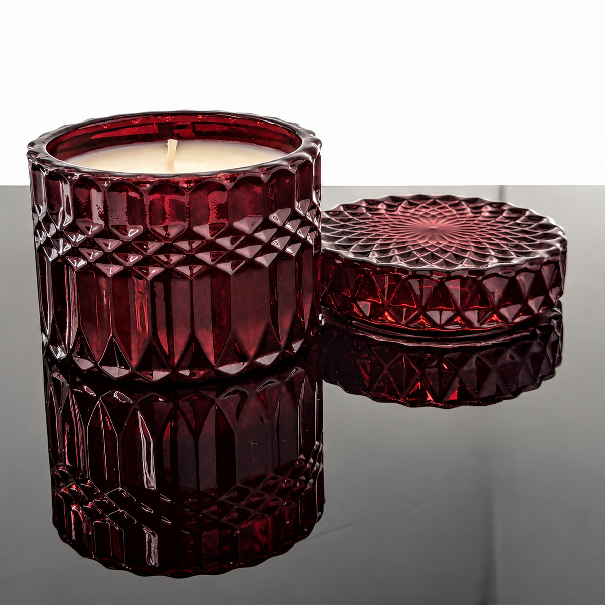 Ritual Candle in oxblood faceted glass with matching lid, reflected on black