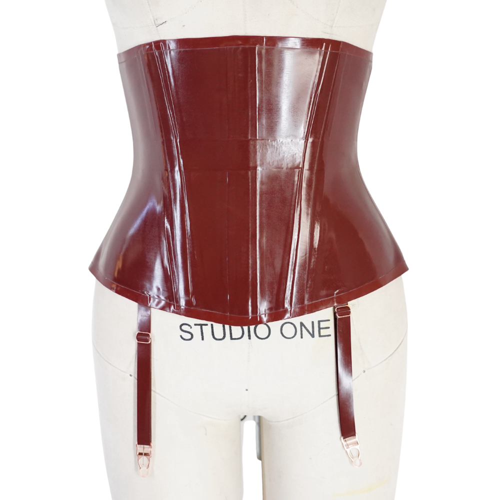 A shiny dark red vinyl corset with garter straps by Vex Inc. | Latex Clothing is displayed on a STUDIO ONE dress form. It features a glossy finish, structured hourglass shape, and Accent Bar detail, and is ready to ship.